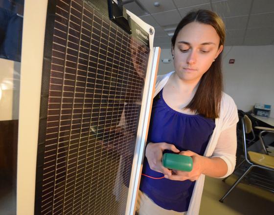 学生在太阳能电池板前看万用表